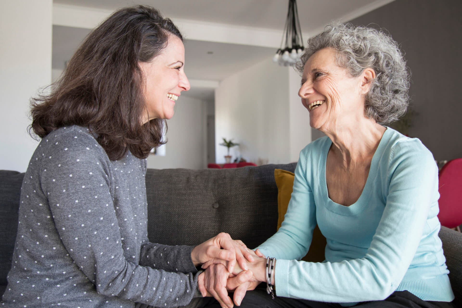 Elderly woman and her daughter laughing and holding hands